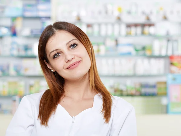 Mulher farmacêutico sobre fundo borrado de prateleiras — Fotografia de Stock