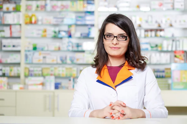 Mulher farmacêutico sobre fundo borrado de prateleiras — Fotografia de Stock