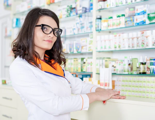 Mulher farmacêutico sobre fundo borrado de prateleiras — Fotografia de Stock