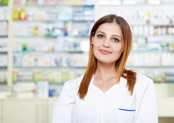 Mulher farmacêutico sobre fundo borrado de prateleiras — Fotografia de Stock