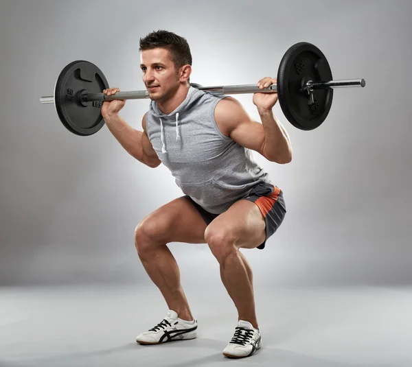 Man doing squats with barbell — Stock Photo, Image