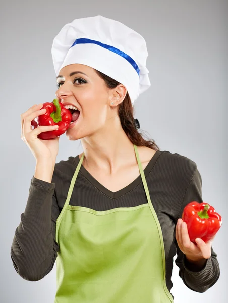 Female cook biting red pepper — Stock Photo, Image