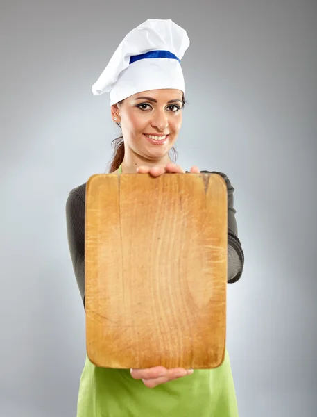 Mulher cozinheiro segurando uma placa de madeira — Fotografia de Stock