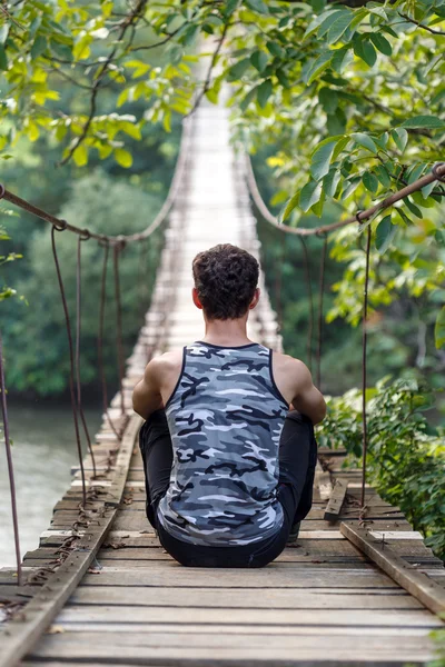 Adolescent garçon assis sur un pont — Photo