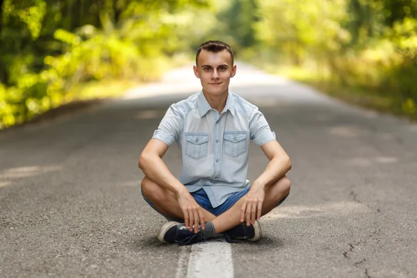 Menino sentado no meio da estrada — Fotografia de Stock