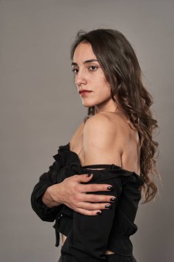 Gri arka planda siyah giyinmiş göz kamaştırıcı model kız.