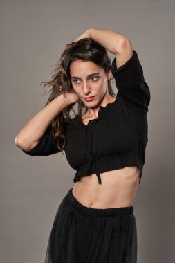 Gri arka planda siyah giyinmiş göz kamaştırıcı model kız.