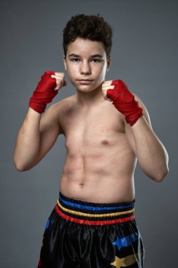 Gri arka planda boks eğitimi almış genç kickboksçu.