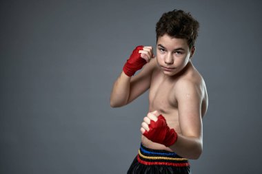 Gri arka planda boks eğitimi almış genç kickboksçu.