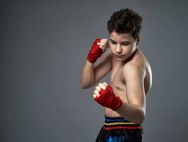 Gri arka planda boks eğitimi almış genç kickboksçu.