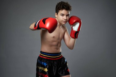 Kırmızı eldivenli genç boksör gri arka planda çeşitli pozlar veriyor.
