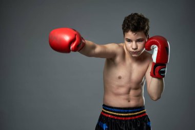 Kırmızı eldivenli genç boksör gri arka planda çeşitli pozlar veriyor.