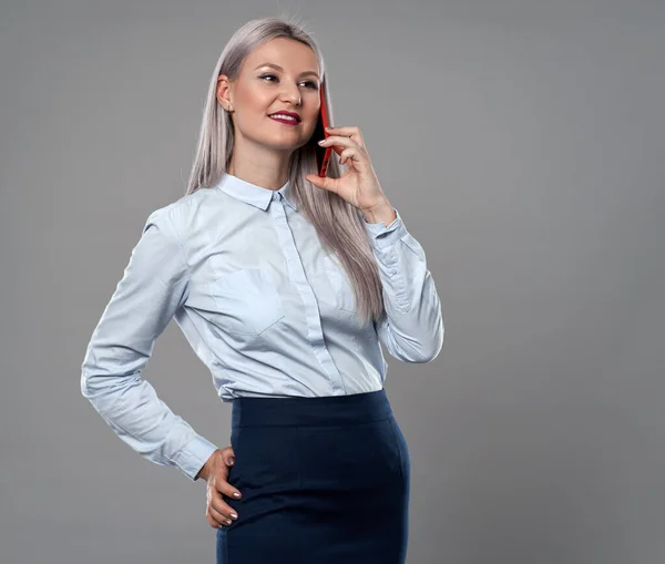 若い実業家は彼女の携帯電話で話すグレーの背景 — ストック写真