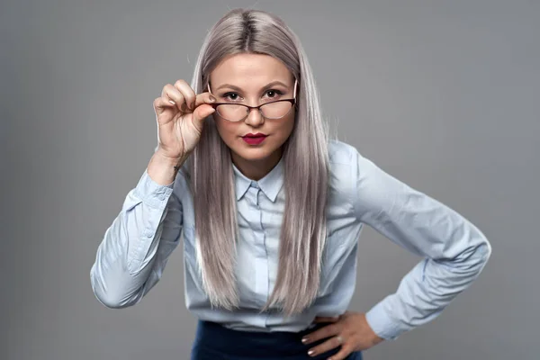 Young businesswoman with an expression of doubt, looking over glasses