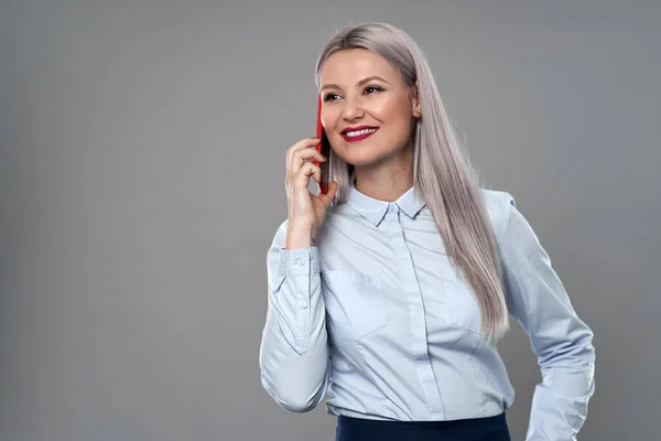 若い実業家は彼女の携帯電話で話すグレーの背景 ストック画像