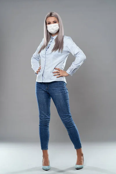 Full body studio portrait of a young businesswoman wearing face mask against coronavirus