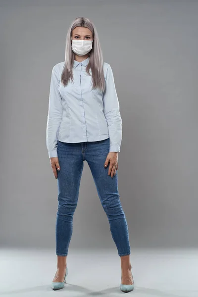 Full body studio portrait of a young businesswoman wearing face mask against coronavirus