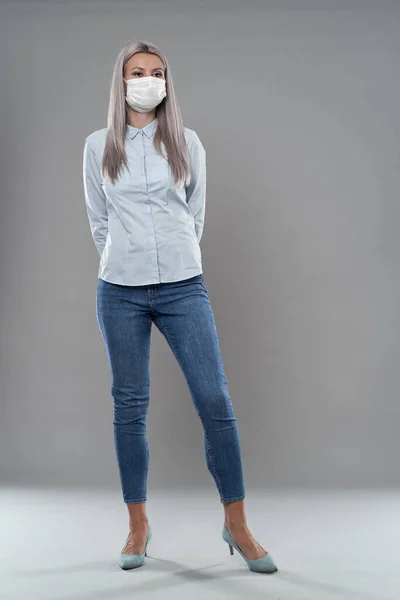 Full body studio portrait of a young businesswoman wearing face mask against coronavirus