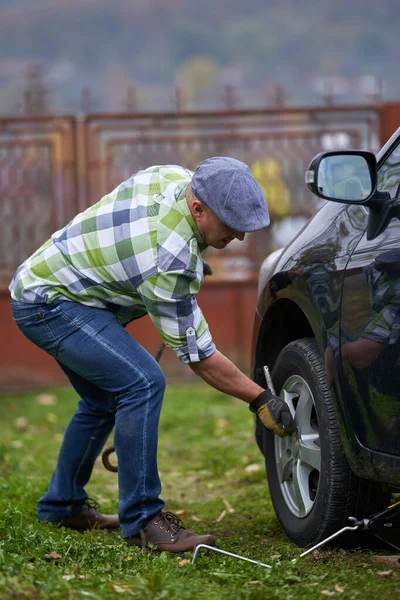 Άνθρωπος Αλλάζει Ένα Σκασμένο Λάστιχο Στο Αυτοκίνητό Του Μόνος Του — Φωτογραφία Αρχείου