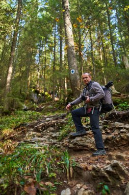 Ağır sırt çantası, tripodu ve dağlarda yürüyüş yapan profesyonel doğa fotoğrafçısı.