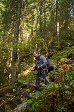 Ağır sırt çantası, tripodu ve dağlarda yürüyüş yapan profesyonel doğa fotoğrafçısı.
