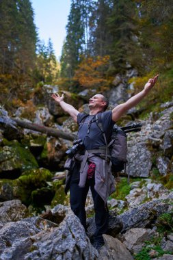 Ağır sırt çantası, tripodu ve dağlarda yürüyüş yapan profesyonel doğa fotoğrafçısı.