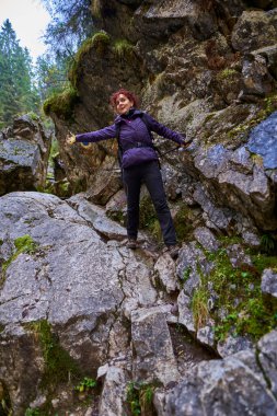 Kireçtaşı dağlarında yürüyen kameralı bir turist kadın.