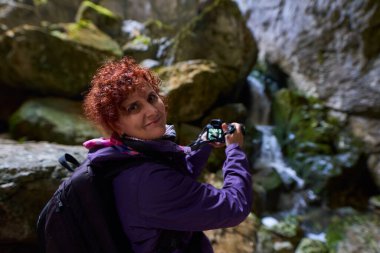 Kireçtaşı dağlarında yürüyen kameralı bir turist kadın.