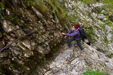 Kireçtaşı dağlarında yürüyen kameralı bir turist kadın.