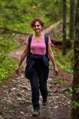 Sırt çantalı aktif bir kadın ormanda yürüyüş yapıyor.