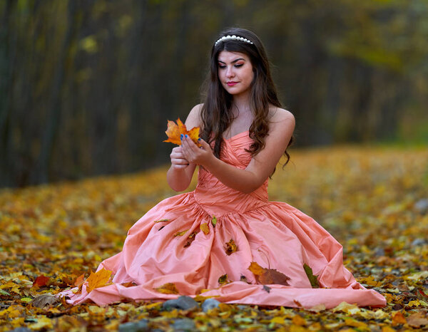 Autumnal beauty portrait of a young woman in an oak forest