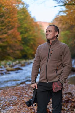 Gün batımında nehir kenarında kamerası olan doğa fotoğrafçısı.