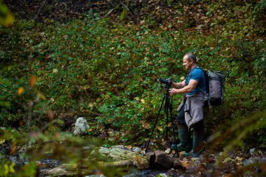 Profesyonel doğa fotoğrafı, büyük sırt çantası, kamera ve tripodlu.