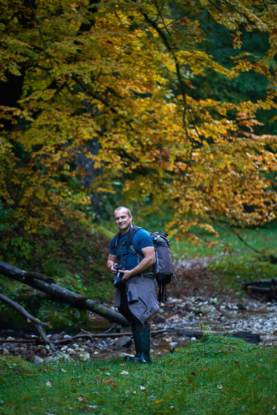 Professional nature photographe with large backpack, camera and tripod