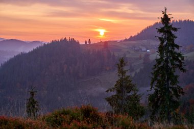 Soğuk bir kasım sabahı güneşin doğuşuyla birlikte çeşitli ormanlarla kaplı dağların manzarası.