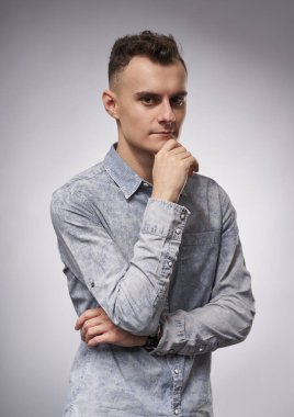 Gri arka planda yakışıklı genç bir iş adamının yakın çekimi.