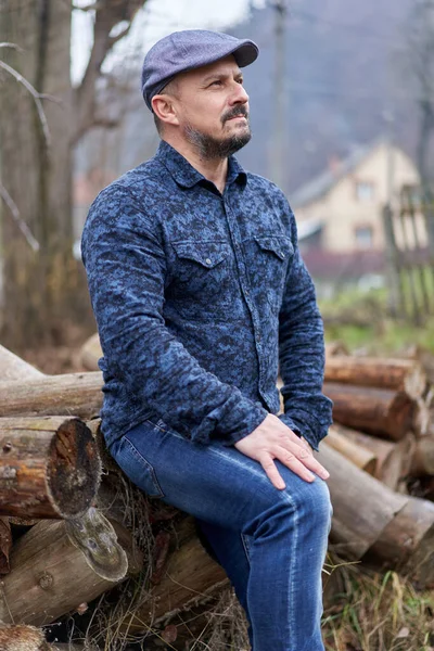 Boer Blauwe Jeans Shirt Pet Zittend Een Stapel Houtblokken Hakken — Stockfoto