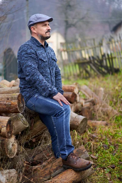 Farmář Modrých Džínách Košili Čepici Sedí Hromadě Klád Které Mají — Stock fotografie