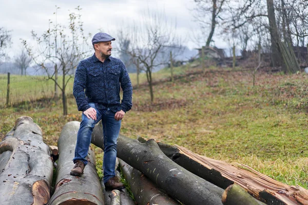 Agricultor Calça Azul Camisa Boné Sentado Uma Pilha Troncos Para — Fotografia de Stock