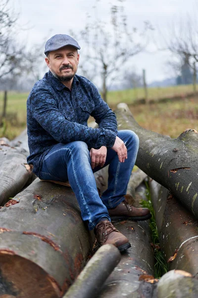 Boer Blauwe Jeans Shirt Pet Zittend Een Stapel Houtblokken Hakken — Stockfoto