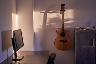 Duvarında gitarı ve bilgisayarı olan bir gencin odası.