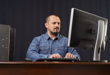 İşadamı masasında ofis belgeleriyle birlikte bilgisayarda çalışıyor.