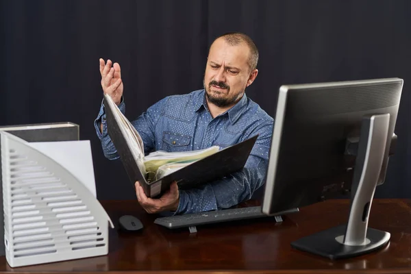 怒っていると不満オフィスの労働者彼の机でコンピュータと文書を扱う — ストック写真