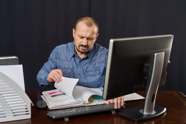 Angry and displeased office worker at his desk working with computer and documents