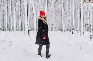 Kışın karlı bir ormanda kırmızı şapkalı beyaz bir kadının portresi.