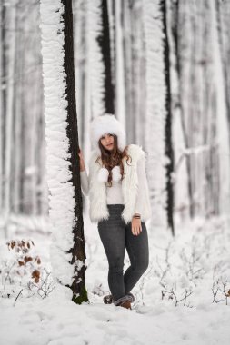 Genç beyaz kadın ormanda karda oynarken eğleniyor.