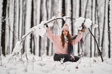 Genç beyaz kadın ormanda karda oynarken eğleniyor.