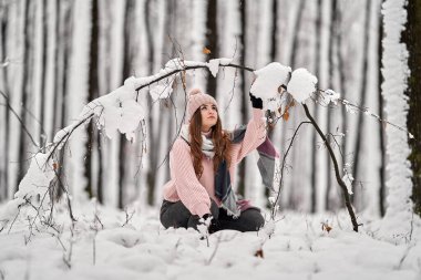 Genç beyaz kadın ormanda karda oynarken eğleniyor.