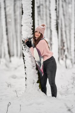 Genç beyaz kadın ormanda karda oynarken eğleniyor.