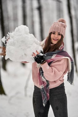 Genç beyaz kadın ormanda karda oynarken eğleniyor.